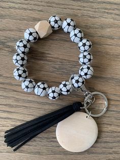 a black and white bracelet with a tasseled charm is shown on a wooden surface