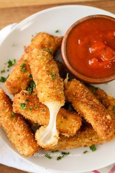 some fried food is on a white plate with a small bowl of sauce in the background