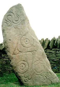 a large rock with carvings on it in the grass