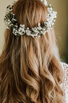 a woman with long hair wearing a white flowered headpiece on top of her head