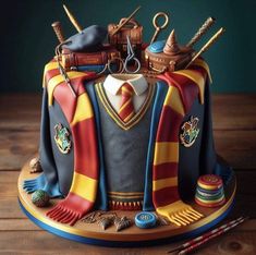 a harry potter birthday cake is decorated with hogwart's robes and other accessories