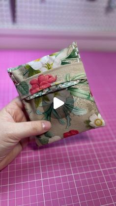 a person is holding a small wallet on a pink cutting mat with the video showing how to fold it