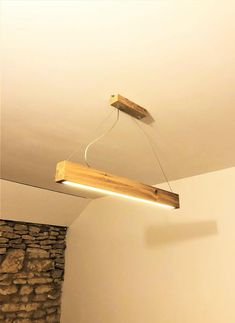 a wooden light hanging from the ceiling in a room with stone wall and white walls