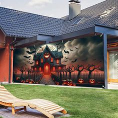 a house with halloween decorations painted on the wall and lawn chairs in front of it