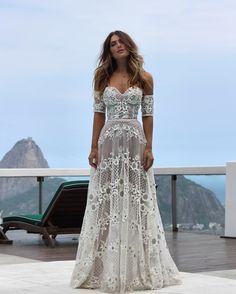 a woman in a white dress standing on a balcony