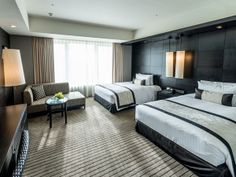 a hotel room with two beds, chairs and a flat screen tv on the wall