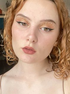 a close up of a woman with makeup on her face and wearing large hoop earrings