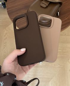 a person holding two cases in their hands, one is brown and the other is tan