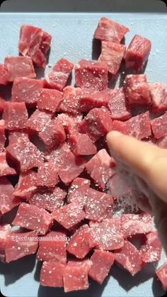 someone is pointing at cubes of meat on a cutting board