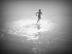 a person is running through the water on a surfboard in black and white photo