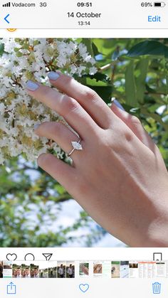 someone's hand with two rings on their fingers and flowers in the foreground