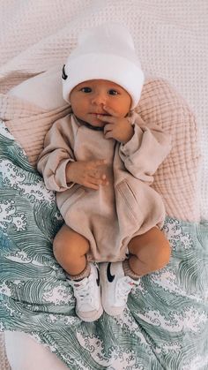 a baby laying on top of a blanket wearing a white hat