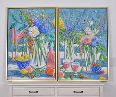 two paintings of vases with flowers and fruit are on display in front of a dresser