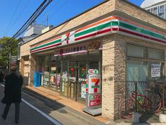 a man walking down the street in front of a small store with bicycles parked outside