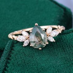 a close up view of a ring with stones on the front and side, sitting on top of a green cloth