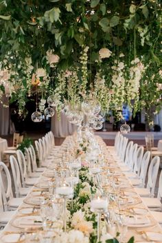 a long table with white flowers and greenery is set up for an elegant dinner