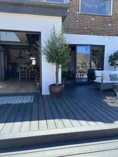 an outdoor deck with potted trees and chairs