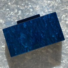 This acrylic party box clutch features a hand swirled acrylic exterior in a mesmerizing blue. Push open the matching acrylic top clasp and inside you will find a black lined interior. Comes with optional gold-toned crossbody chain to carry as a shoulder bag or you can add one of our acrylic chains for even more style. Fits an iPhone Plus with case. ▪️Length: 7.25", Height: 3.75", Depth: 1.75" ▪️Materials: acrylic, plated metals, cotton/polyester lining. Small variations can happen in the product Trendy Blue Clutch For Formal Occasions, Modern Blue Clutch For Formal Occasions, Trendy Blue Clutch For Gift, Trendy Blue Evening Clutch, Blue Rectangular Clutch For Events, Blue Rectangular Clutch For Formal Occasions, Blue Rectangular Clutch For Evening, Acrylic Clutch, Party Box