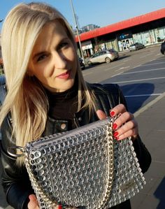 a woman in black jacket holding a silver purse