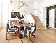 a dining room table with chairs and a vase filled with flowers on top of it