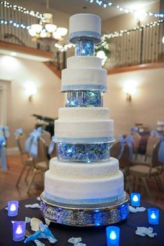 a large white wedding cake sitting on top of a table covered in blue and white decorations