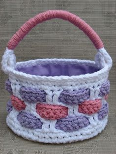 a crocheted basket with pink and purple handles