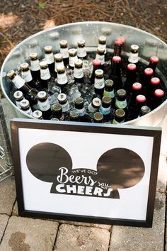 a metal bucket filled with bottles of beer on top of a brick floor next to a sign