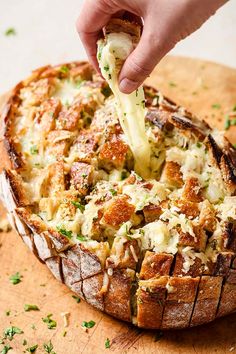 a person dipping cheese into a baked bread dish