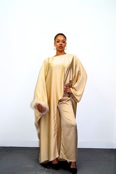 Embrace timeless elegance with our exquisite Satin Abaya Co-Ord Set. This stunning two-piece ensemble features a luxurious, soft-flowing satin fabric that drapes beautifully and flatters your figure. The elegant abaya boasts a modest silhouette, perfect for everyday wear or special occasions. The highlight of this set is the exquisite fur trim. This touch of luxury adds a touch of sophistication and warmth to the design, making it perfect for cooler evenings or formal events. Key Features Luxurious Satin Fabric: Experience the soft, smooth feel of premium satin that flatters your form. Elegant Abaya Silhouette: This modest design offers full coverage while maintaining a stylish and graceful drape. Delicate Fur Trim: Elevate your look with a touch of luxury and warmth. Two-Piece Co-Ord Set: Elegant Cape Sets For Eid, Evening Maxi Sets For Eid, Elegant Eid Cape Sets, Chic Long Abaya For Eid, Chic Floor-length Abaya, Elegant Beige Floor-length Sets, Elegant Cape Abaya For Evening, Elegant Cape-style Evening Abaya, Elegant Cape Style Evening Abaya