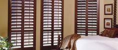 a bedroom with wooden shutters and white bed