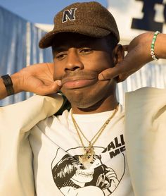 a man wearing a hat and holding his hand up to his face while posing for the camera