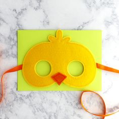 a paper pumpkin mask sitting on top of a green piece of paper next to a pair of scissors