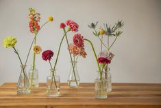 four vases with flowers in them sitting on a table