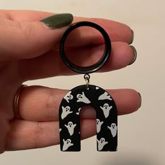 a person holding a black and white keychain with ghost charms on it