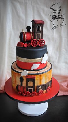 a three tiered cake with a train on it's side and red wheels