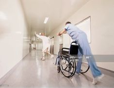 a man pushing a woman in a wheelchair down a hallway with other people walking by