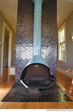 a room with a large blue stove in it's center and wood floors on the other side