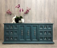 a blue dresser with flowers and vases on top