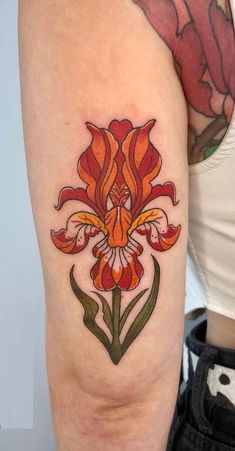 a woman's arm with an orange and red flower tattoo on the left thigh