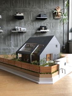 a model of a house on display in front of a wall with bookshelves