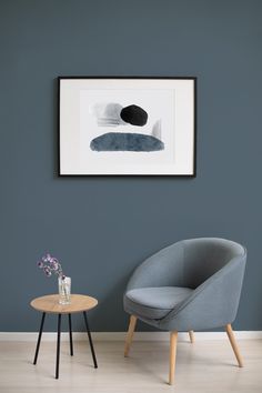 a chair and table in front of a blue wall with a painting on the wall