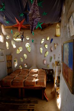 a bed room with a neatly made bed and lots of stars hanging from the ceiling