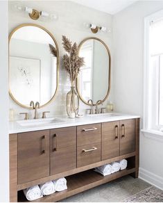 a bathroom with two round mirrors above the sink and towels on the rack in front of it