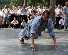 a man is doing push ups in front of a crowd with his hands on the ground