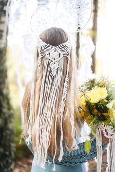 a woman with long hair holding flowers in her hand and wearing a white headdress