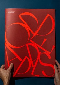 a person holding up a book with red letters on it