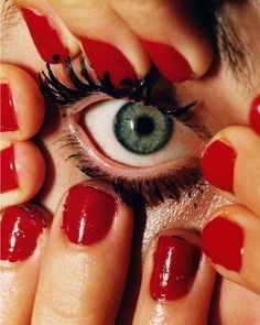 a woman's eye with red nail polish on her fingers and an eyeball in the middle