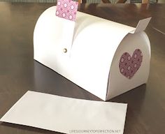 a white mailbox with a pink heart on it and a piece of paper sticking out of the top