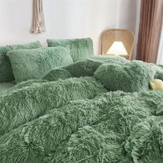 a bed covered in green fluffy pillows and blankets