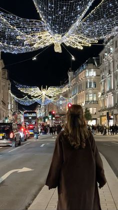 a woman is walking down the street with lights all over her head and cars parked on the side of the road